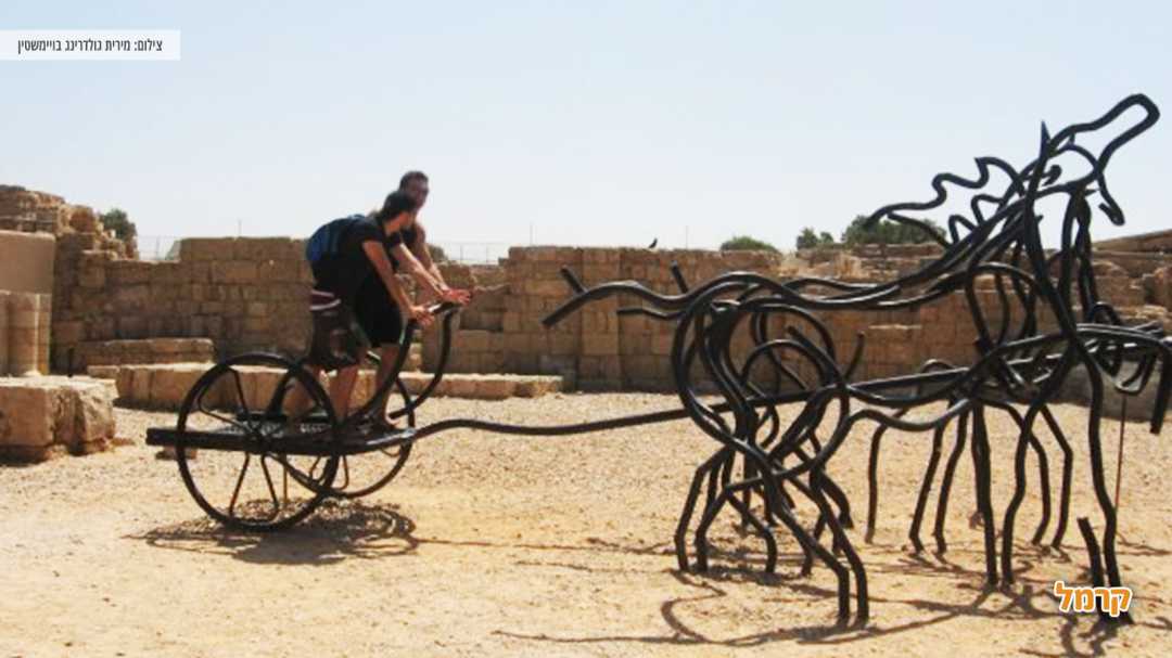 אנשים יושבים על פסל סוס עם כרכרה