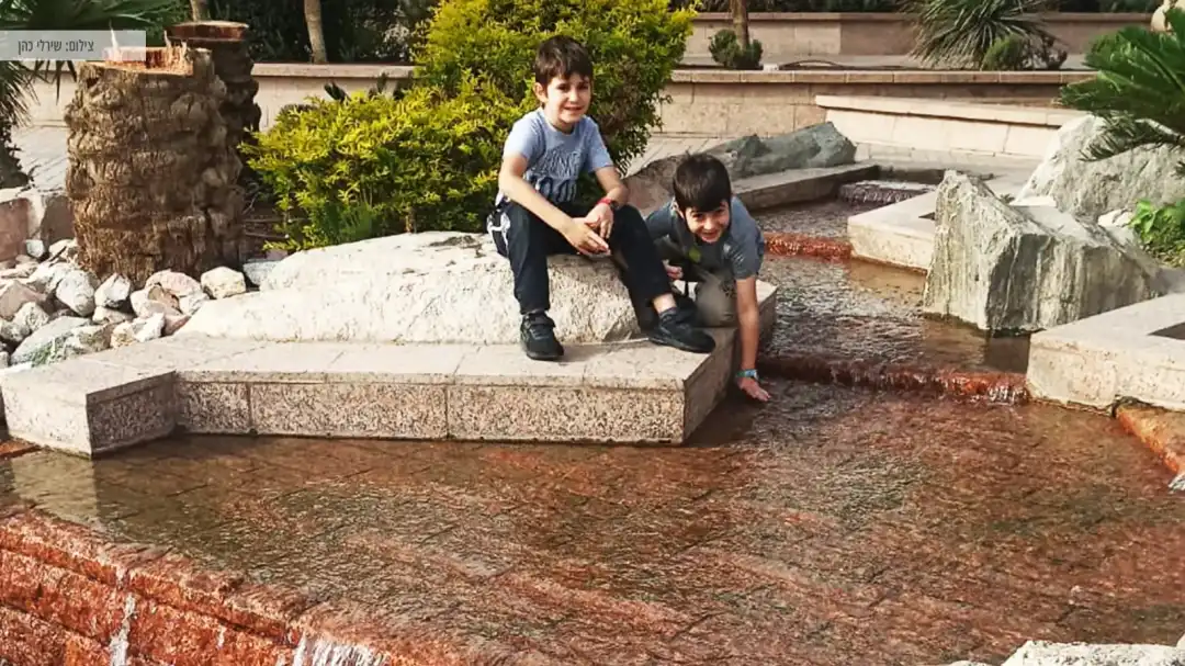 2 ילדים משחקים במזרקה בטיילת