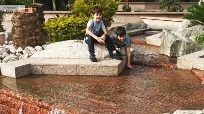 2 ילדים משחקים במזרקה בטיילת