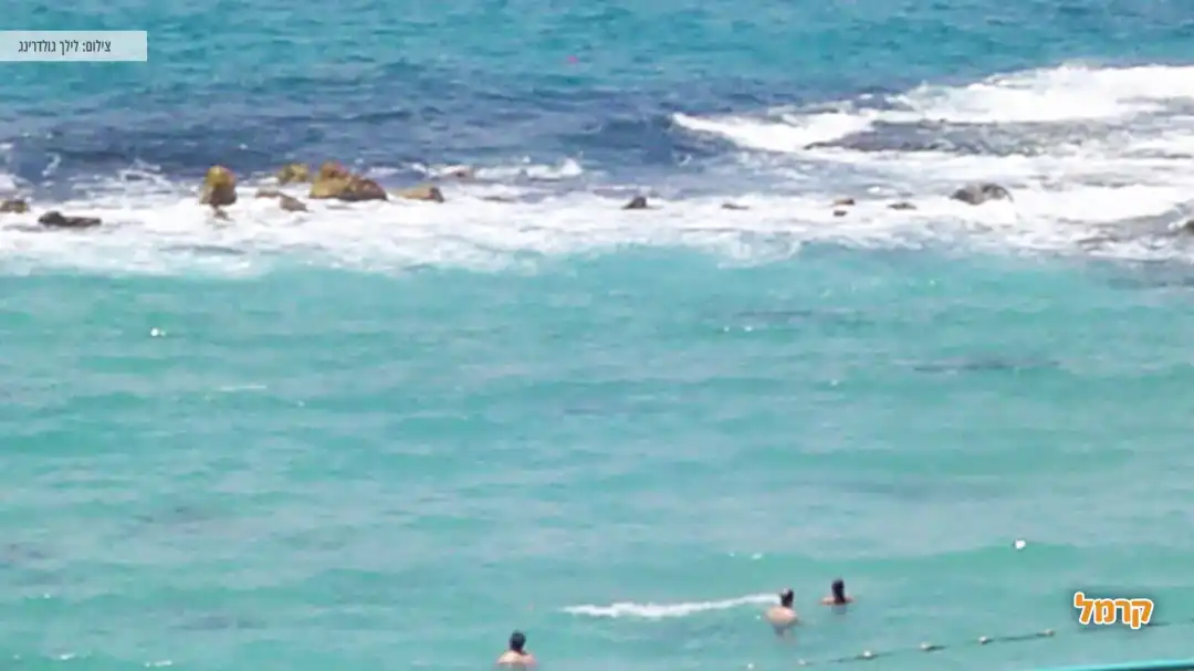 אנשים נהנים במי הים בחוף אכזיב