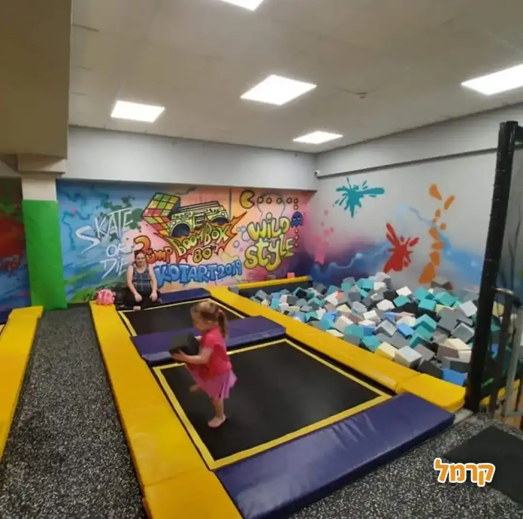 ילדה נהנת מטרמפולינות ובריכת ספוגים